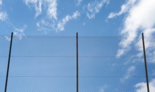 Metal Rabitz mesh fence against blue sky
